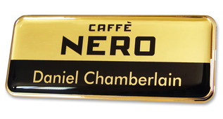 A golden plastic executive name badge with the leyend: "Caffé Nero"